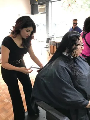 Crystal Morales cutting a seated client's long dark hair